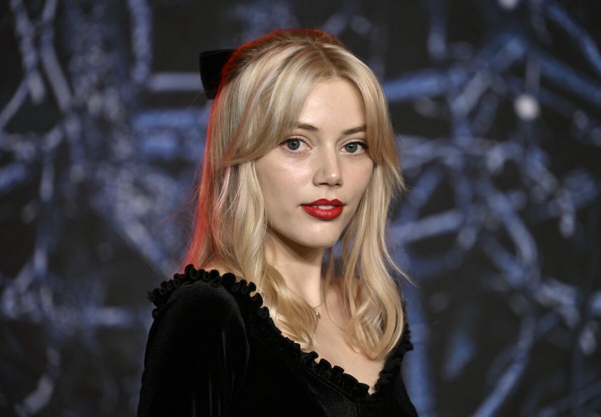 A young woman with blond hair and wearing a black dress