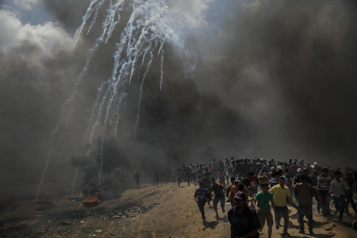 Palestinians run for cover from tear gas fired by Israeli forces near the border between the Gaza Strip and Israel.