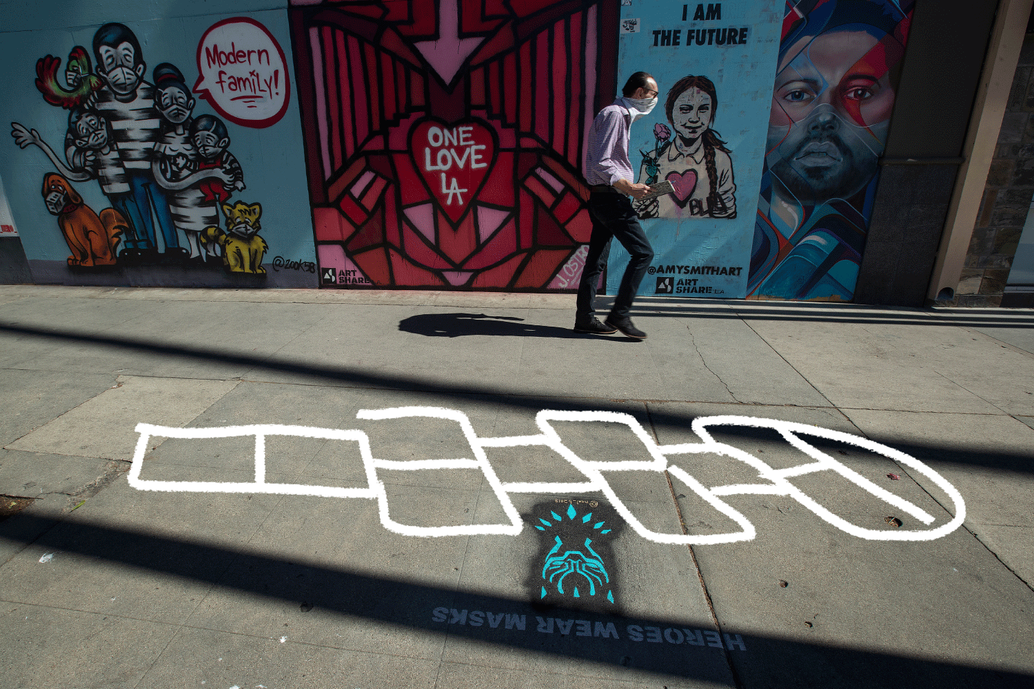 A GIF of a numbers appearing on a hopscotch grid on a city sidewalk next to murals.