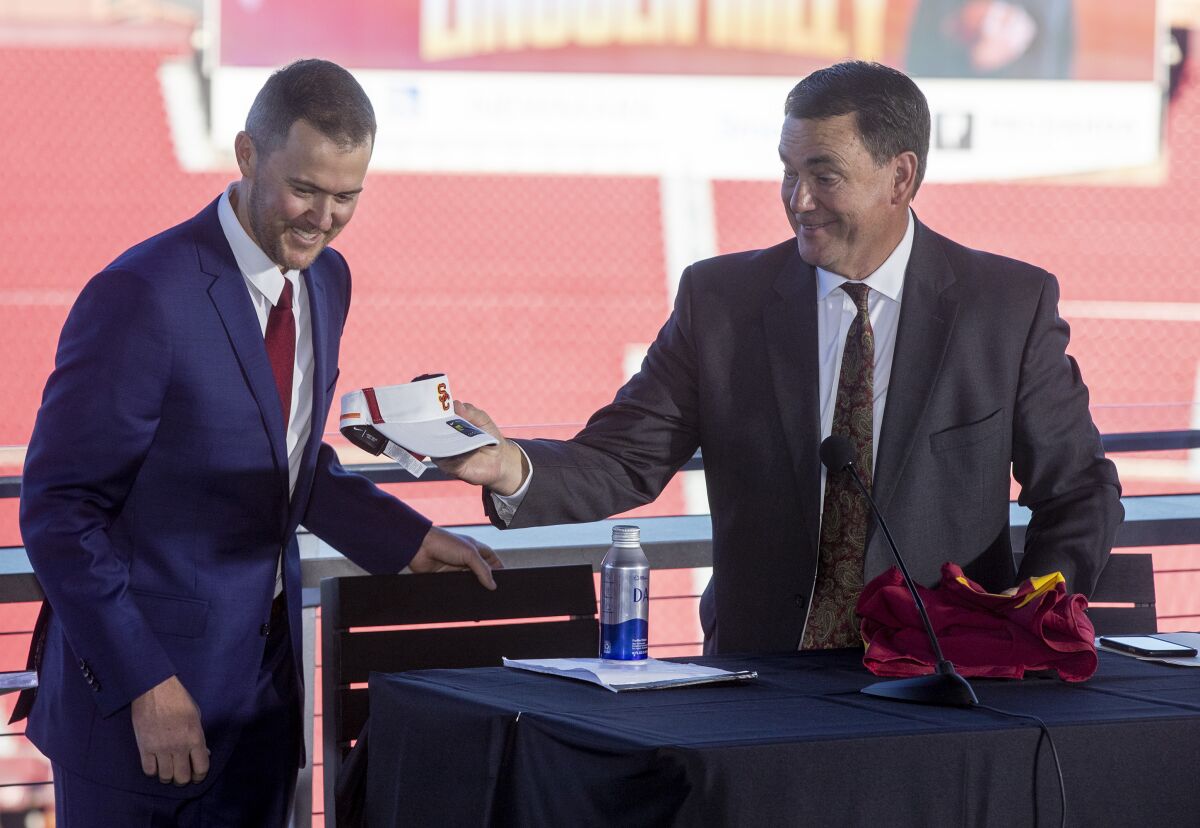 USC athletic director Mike Bohn, right, hands new football coach Lincoln Riley a USC visor.