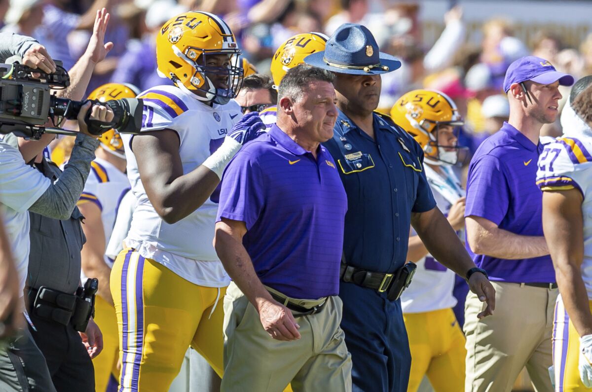 LSU head coach Ed Orgeron is escorted onto the field after LSU's 49-42 win over Florida in an NCAA college football game, Saturday, Oct. 16, 2021, in Baton Rouge, La. LSU and coach Orgeron have agreed to part ways after this season, according to multiple media reports Sunday, Oct. 17, 21 months after he led the Tigers to a national championship with what is considered one of the greatest teams in college football history. (Scott Clause/The Daily Advertiser via AP)