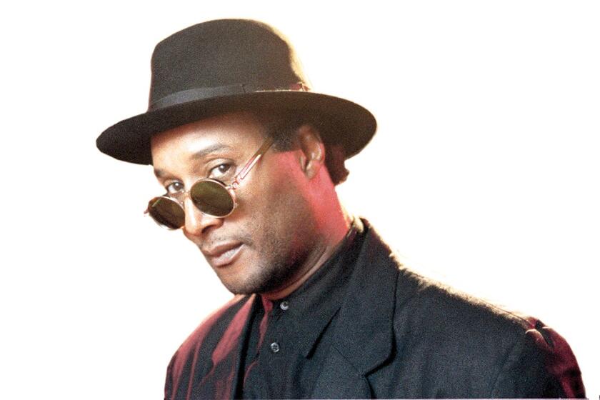 A man in a black suit, hat and sunglasses