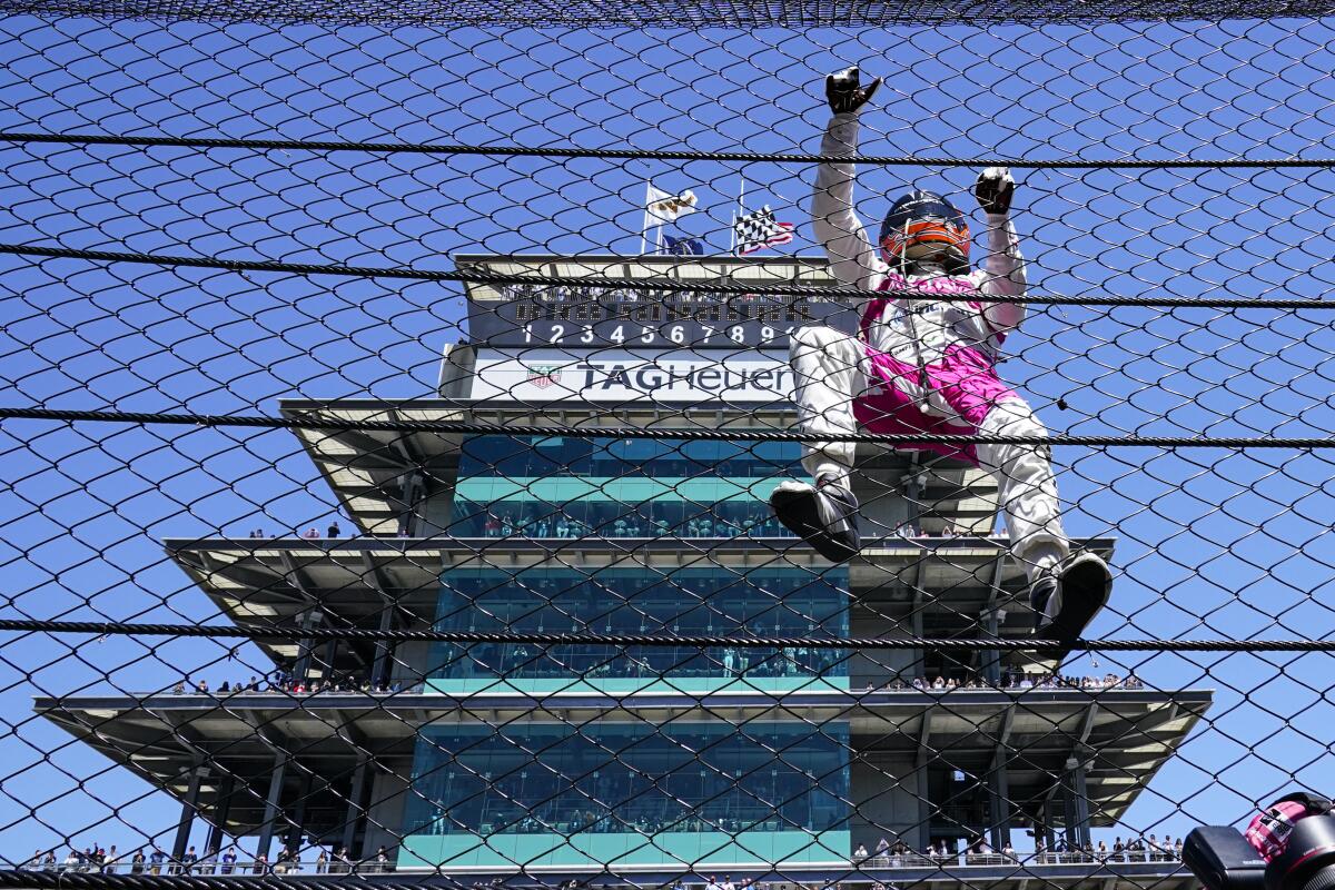 Helio Castroneves climbs the safety fence along the start/finish line after winning the Indianapolis 500 on Sunday.