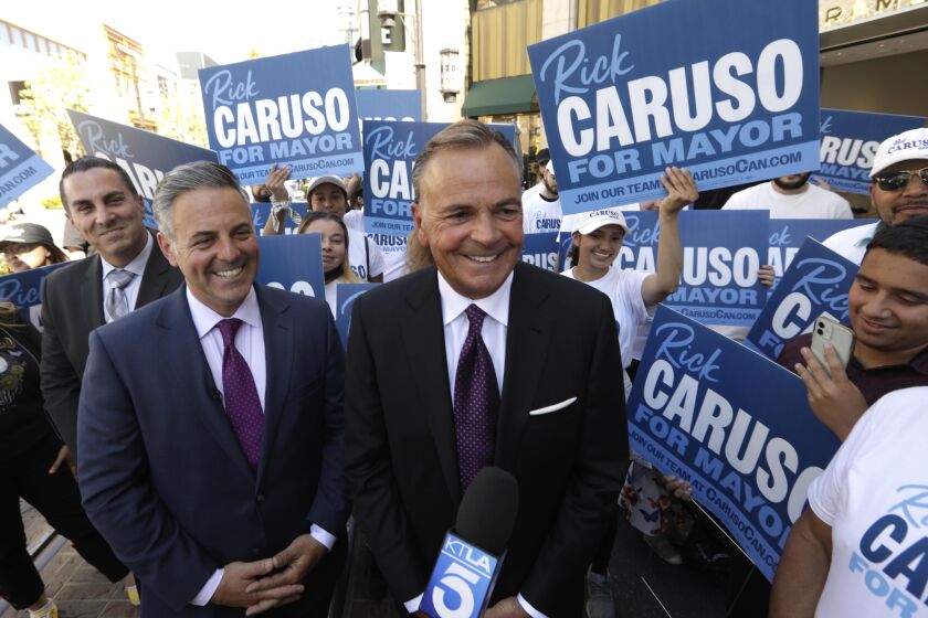 LOS ANGELES, CA - MAY 12, 2022 - - Los Angeles City Councilman Joe Buscaino, left, and businessman Rick Caruso are surrounded by supporters after Buscaino announced that he's dropping out of Los Angeles mayoral race and putting his support behind Caruso for mayor of Los Angeles at The Grove in Los Angeles on May 12, 2022. (Genaro Molina / Los Angeles Times)