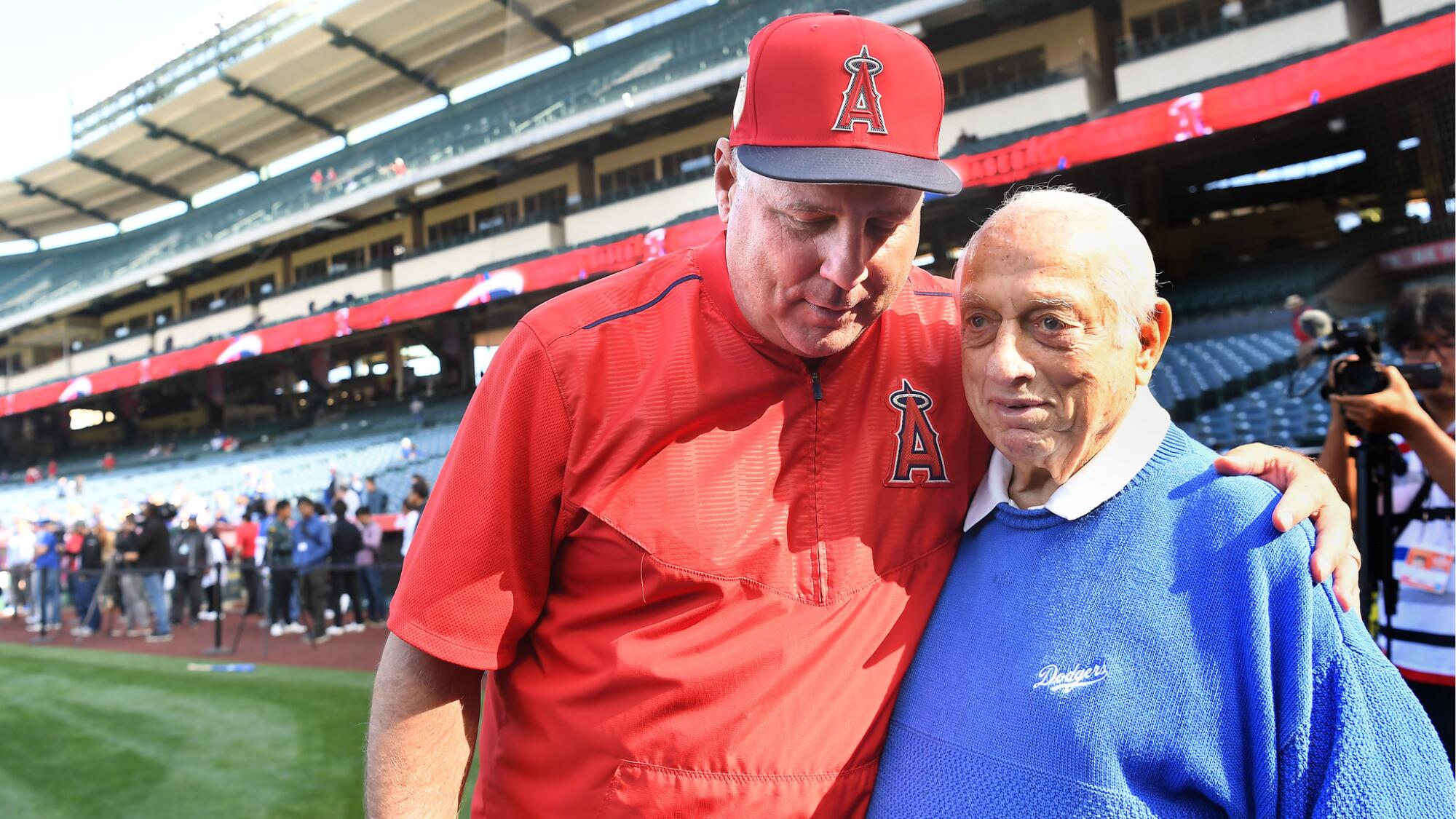 Angels manager Mike Scioscia, who played for Tommy Lasorda with the Dodgers, gives him a hug before a 2018 exhibition game.