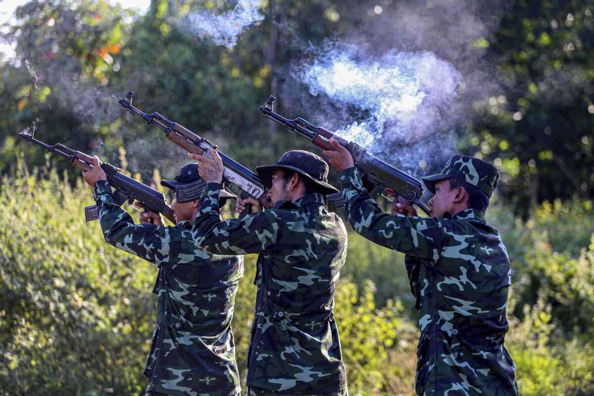 People in military fatigues shoot long guns.