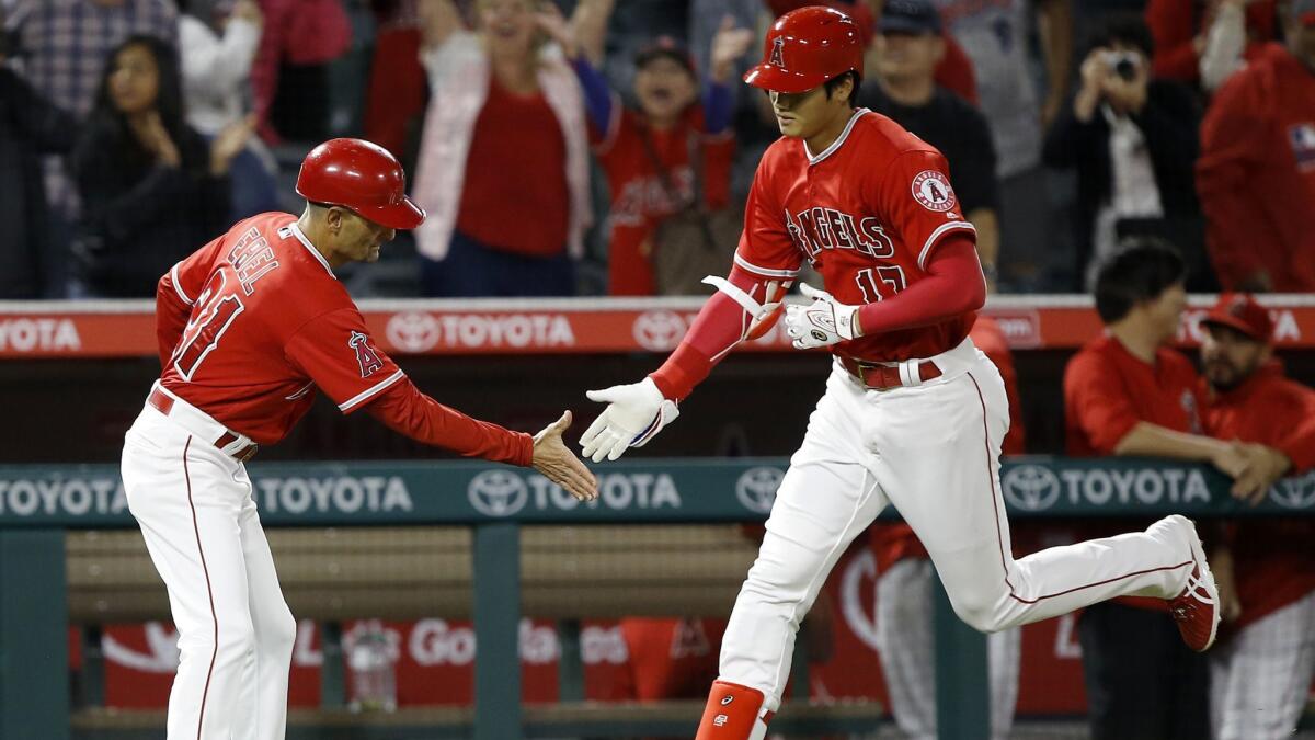 Shohei Ohtani gets a congratulations from third base coach Dino Ebel after hitting a solo home run against the Tampa Bay Rays during the ninth inning on May 17.