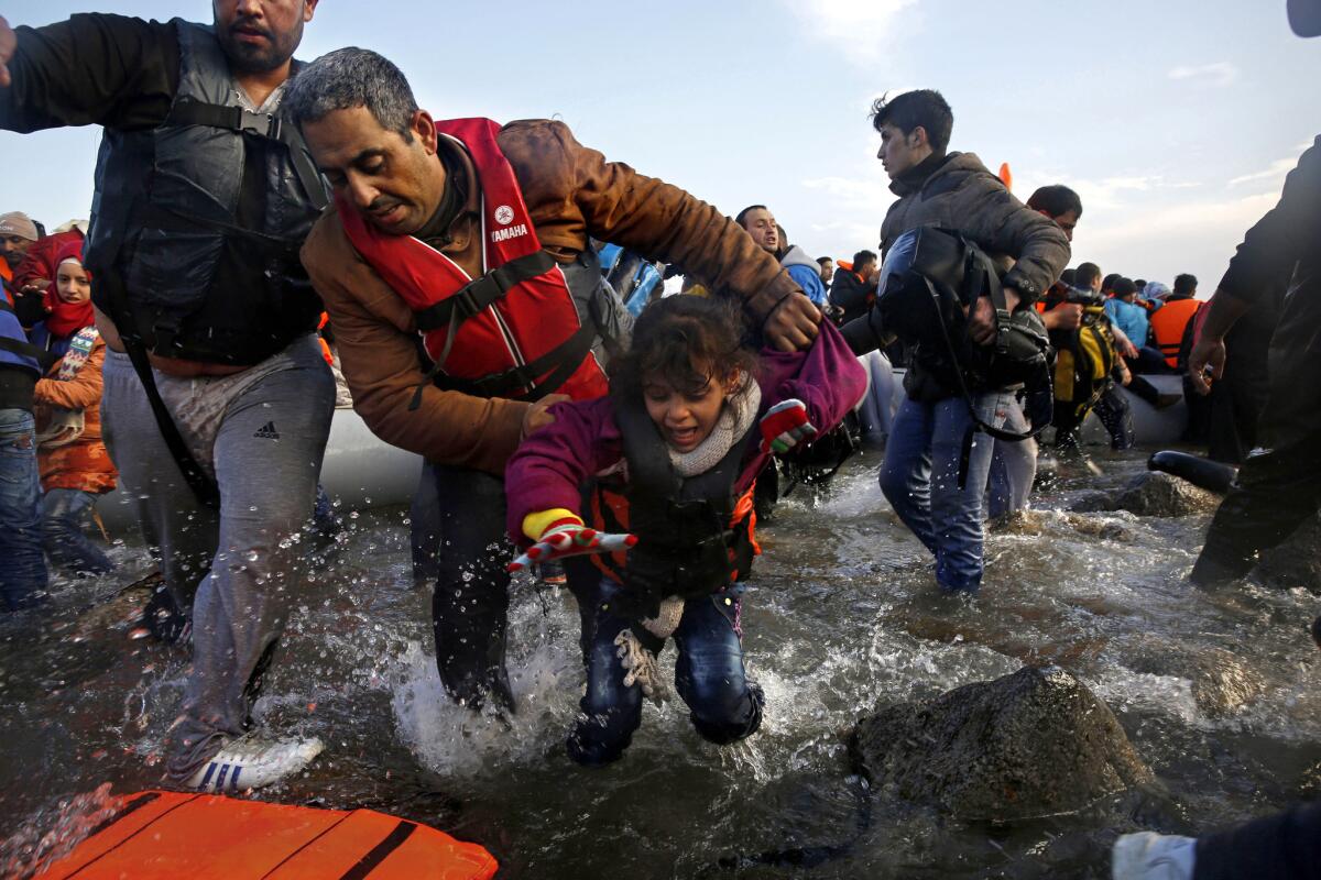 In choppy seas, a Syrian father helps his daughter off the raft that brought them from Turkey to the Greek island of Lesbos, some of the 3,000 arriving daily during the months of October and November 2015.