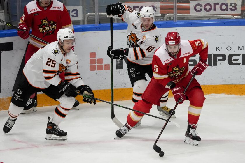FILE - Kunlun Red Star's Ryan Sproul, right, of Canada, fifths for the puck with Amur's Radan Lenc, left, during the Kontinental Hockey League ice hockey match between Kunlun Red Star Beijing and Amur Khabarovsk in Mytishchi, just outside Moscow, Russia, on Nov. 15, 2021. North Americans playing in the Russia-based KHL have been put in a difficult position amid calls from the U.S and Canadian governments for them to leave the country because of the war in Ukraine. (AP Photo/Alexander Zemlianichenko, File)
