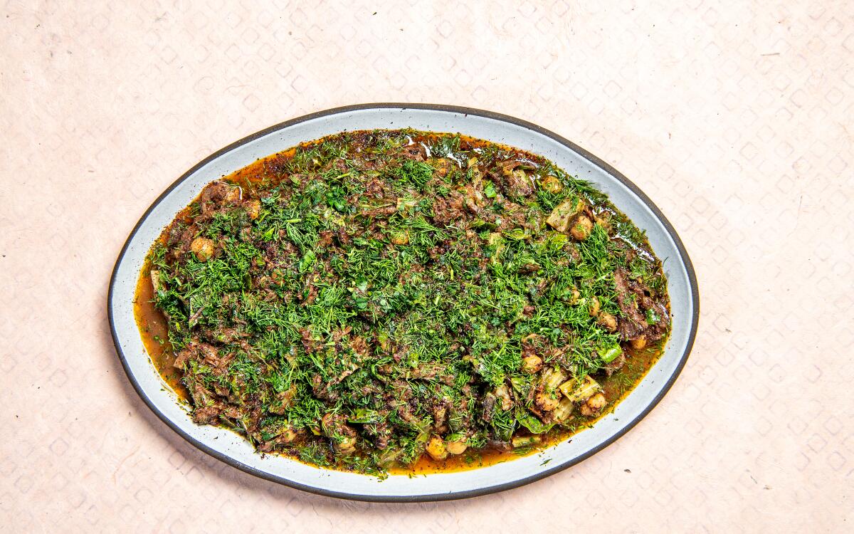 Sumaqqiyeh  — oxtail stew with chard, sumac, and tahini — on an oval plate