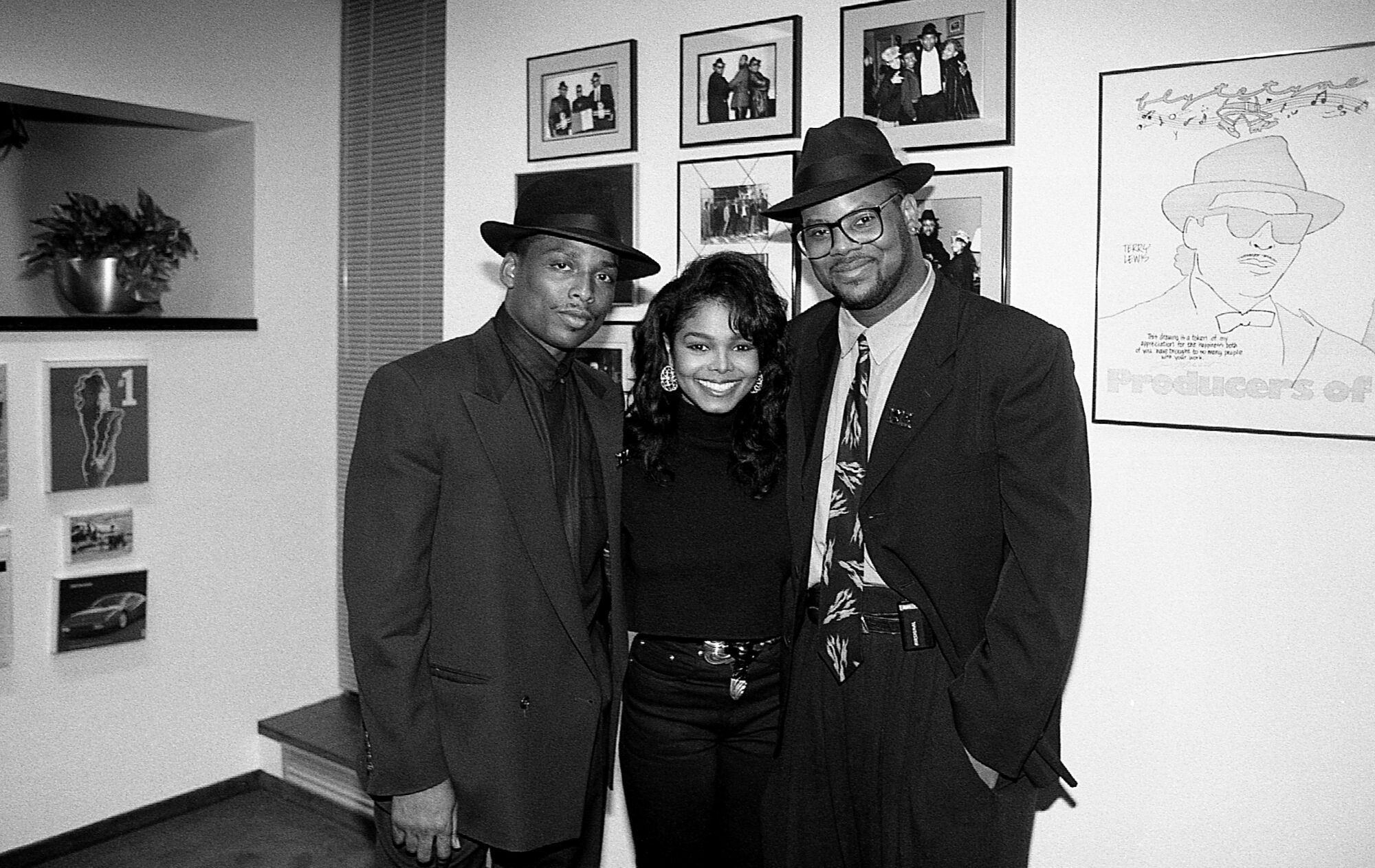 A black-and-white photo of two men and a woman posing together 