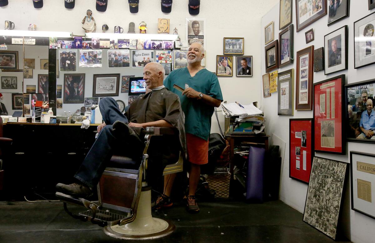 Lawrence Tolliver, right, talks politics while cutting hair at his barber shop in South Los Angeles on Thursday, Oct. 6.