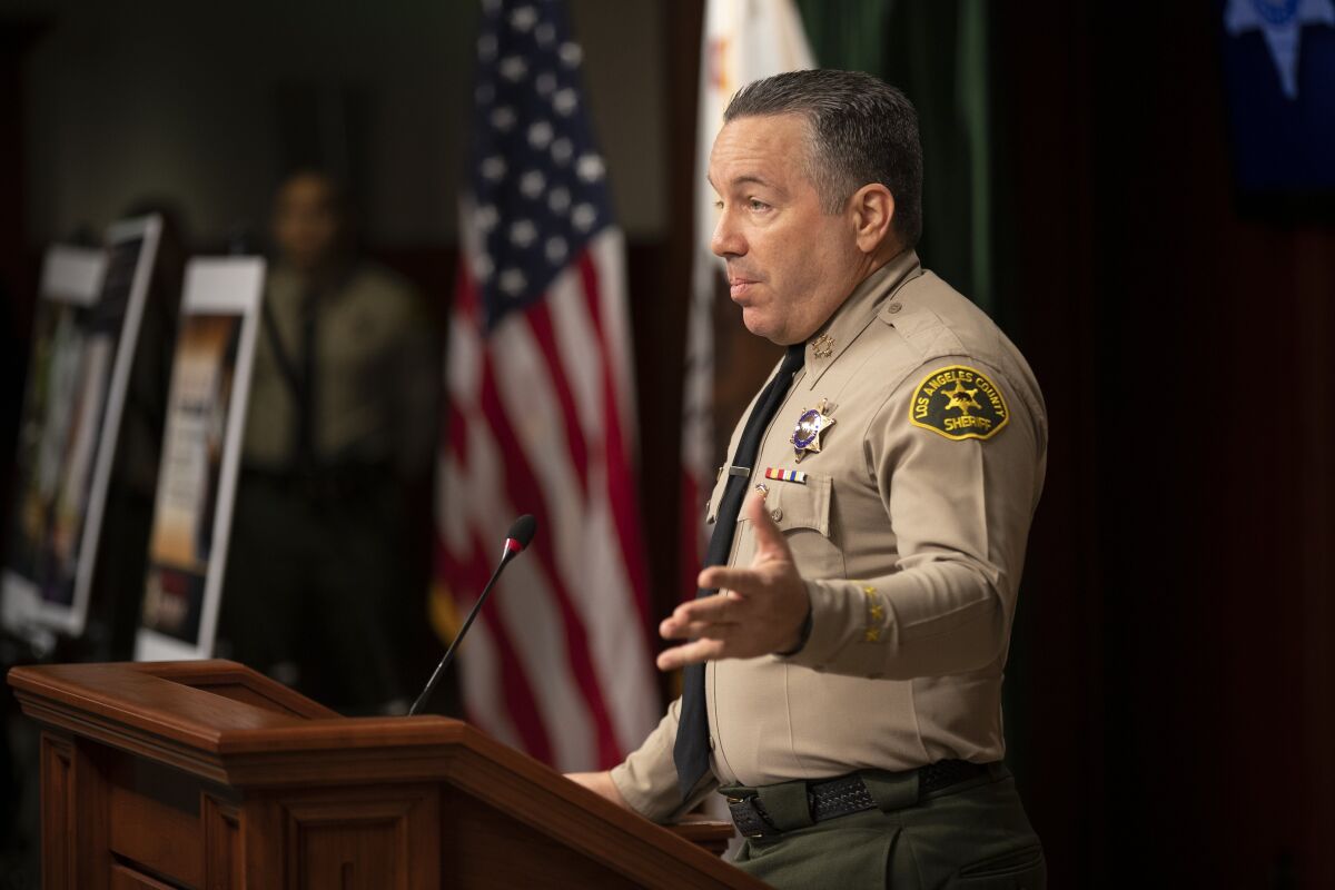 Sheriff Alex Villanueva gestures as he speaks at a lectern during a news conference