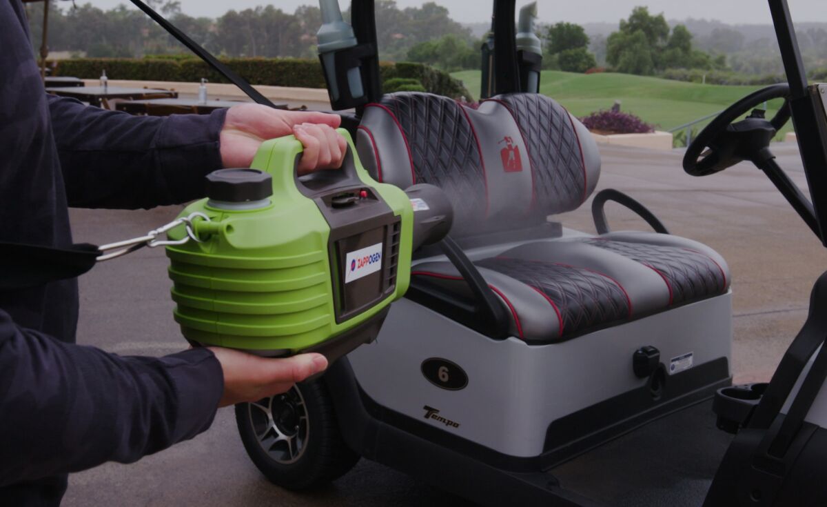 The Zappogen electro-sprayer works to disinfect a golf cart.