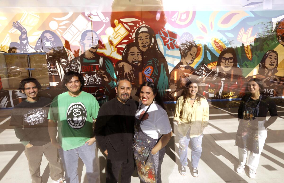 six people in front of a mural