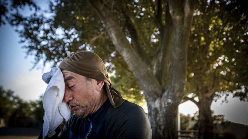 Guillermo Salazar of Reseda wipes sweat from his forehead during a summer heat wave. New research identifies multiple ways that climate change is associated with poor mental health.