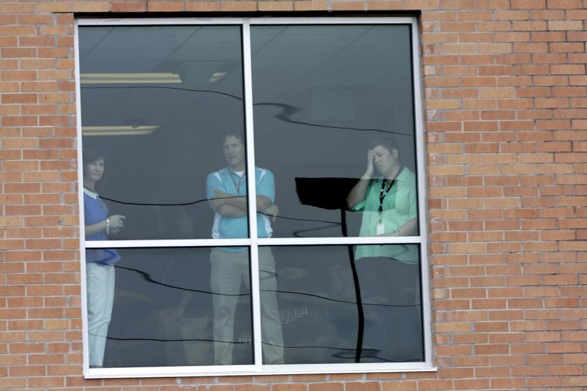 People look out a window at Spring High School in Spring, Texas, as students are loaded onto buses Wednesday after a 17-year-old student was stabbed to death and three others were injured in a fight at the Houston-area campus.