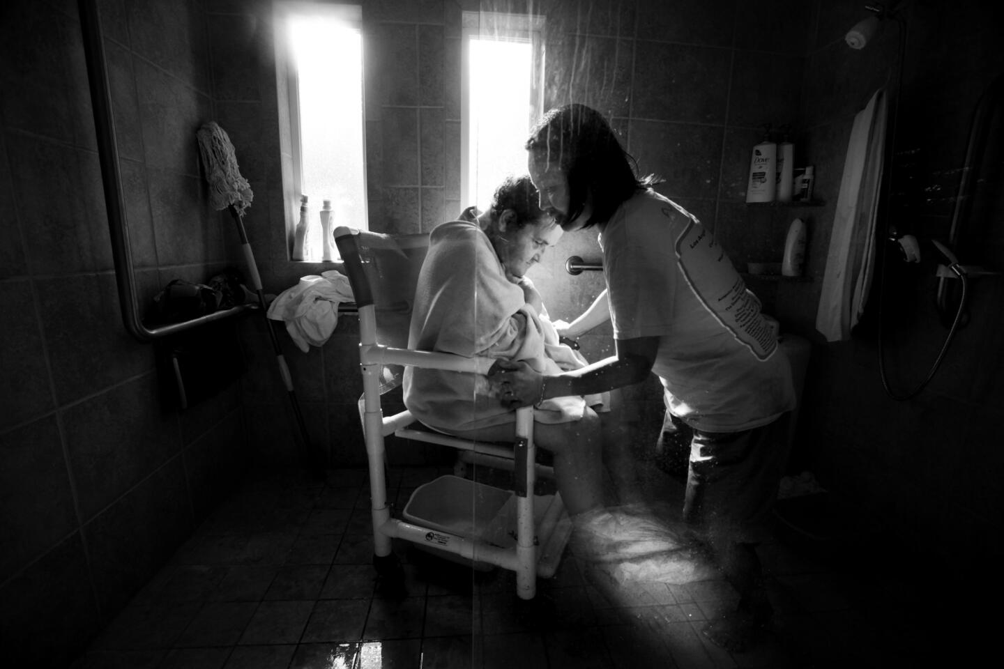 Caregiver Didi Salcedo baths Evelyn Corsini. Evelyn later said, "I don't like the idea of having to be dependent on anybody. But if I had to be, I couldn't have picked a better person to help me." Evelyn's family have stitched together 24-hour care so that she can stay in her own home.
