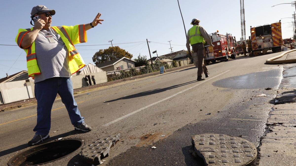 Dan Rodriguez, a supervisor with the Los Angeles Sanitation Department, stands near a manhole cover that was sheared in two.