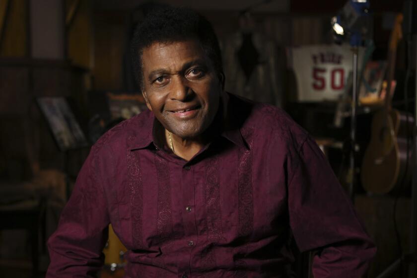 Charley Pride, decked out in a burgundy shirt, sits in his recording studio
