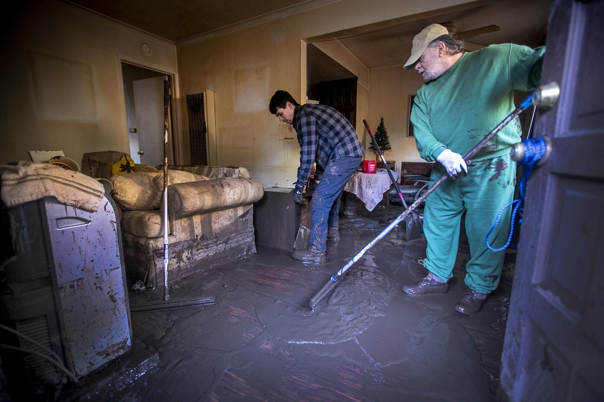Two men stand on a room's muddy floor