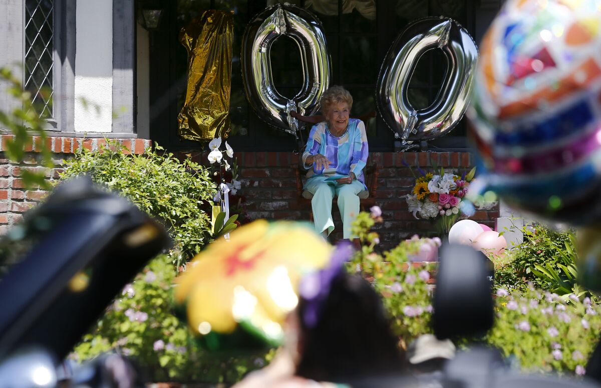 Dancer Joan Bayley marks her 100th birthday by watching a parade from her porch