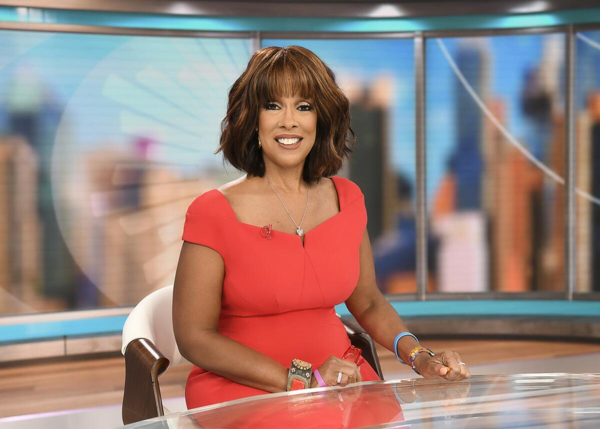 A TV anchor in a red dress at her desk 