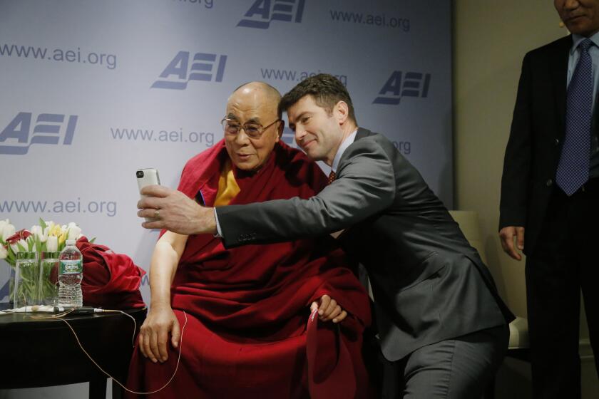 Tibetan spiritual leader the Dalai Lama poses for a "selfie" with blogger and activist Alek Boyd on Thursday during a break between panel discussions at the American Enterprise Institute in Washington.
