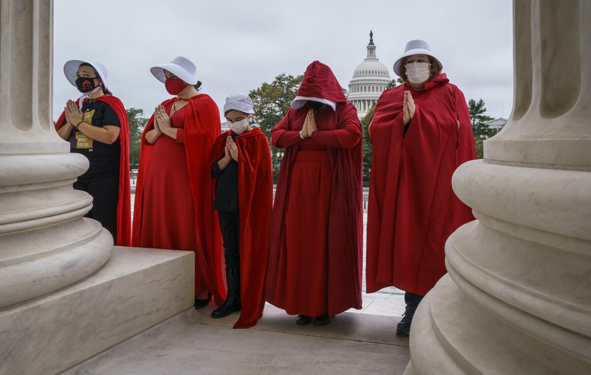 Activists dressed as characters from "The Handmaid's Tale" wear red robes and white hats. 