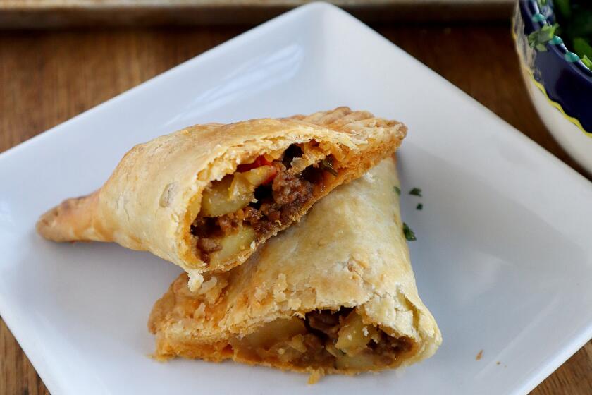 A savory handpie stuffed with Mexican chorizo and potato is presented on a plate, cut in half.
