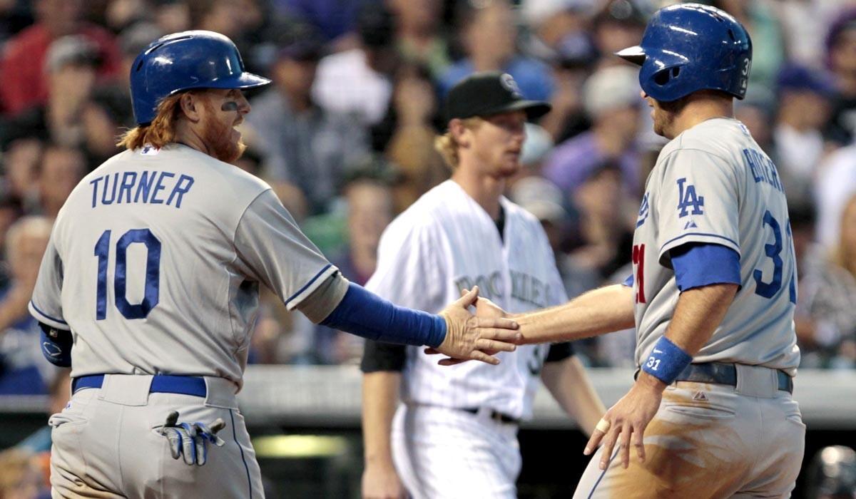 Dodgers third baseman Justin Turner (10) congratulates catcher Drew Butera (31) after they scored in the sixth inning on a single by Dee Gordon (not pictured) off Rockies rookie pitcher Eddie Butler (background) on Friday night in Denver.