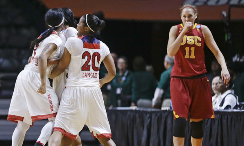 USC's Cassie Harberts, right, walks back to her team's bench as St. John's guard Keylantra Langley, center, celebrates with her teammates immediately following a game-clinching three-pointer by Briana Brown in the Trojans' 71-68 loss in the opening round of the women's NCAA tournament Saturday.