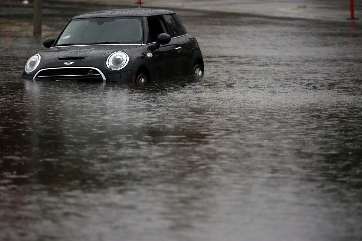 A black Mini Cooper is stranded in high standing water on Burbank Blvd near Balboa Golf Course in Encino.