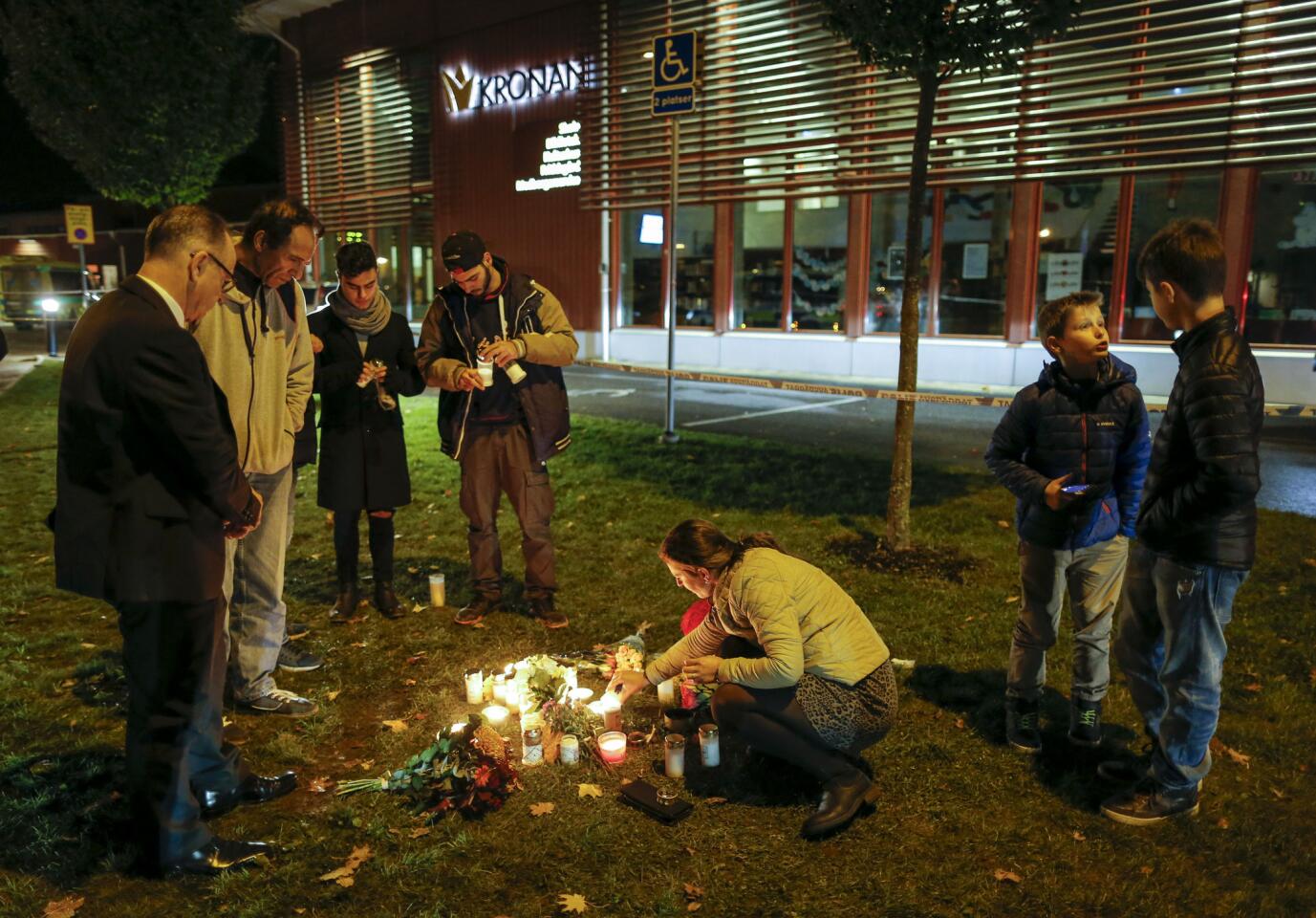 People light candles and lay flower tributes outside the school where a masked man stabbed four people Oct. 22, 2015, in Trollhattan, Sweden.