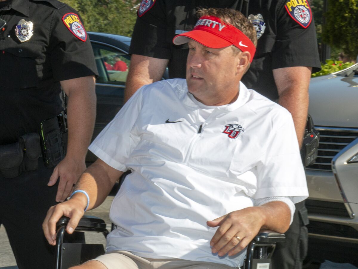 FILE - In this Aug. 31, 2019, file photo, Liberty head football coach Hugh Freeze arrives to coach from a wheelchair in the coaches' box against Syracuse in an NCAA college football game in Lynchburg, Va. Freeze knows that part of his story as Liberty’s football coach is about his own redemption, and he’s fine with that. And in a season when school's administration is embroiled in very public legal battles, he hopes the No. 25 Flames offer some respite. (AP Photo/Matt Bell, File)