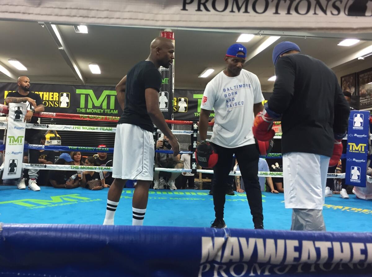 Floyd Mayweather Jr. talks to junior lightweight champion Gervonta Davis after Mayweather's final workout session before his match with Conor McGregor.