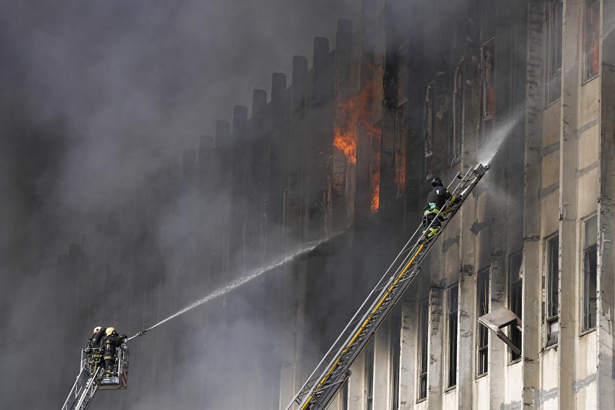 Firefighters spray water on a burning building.