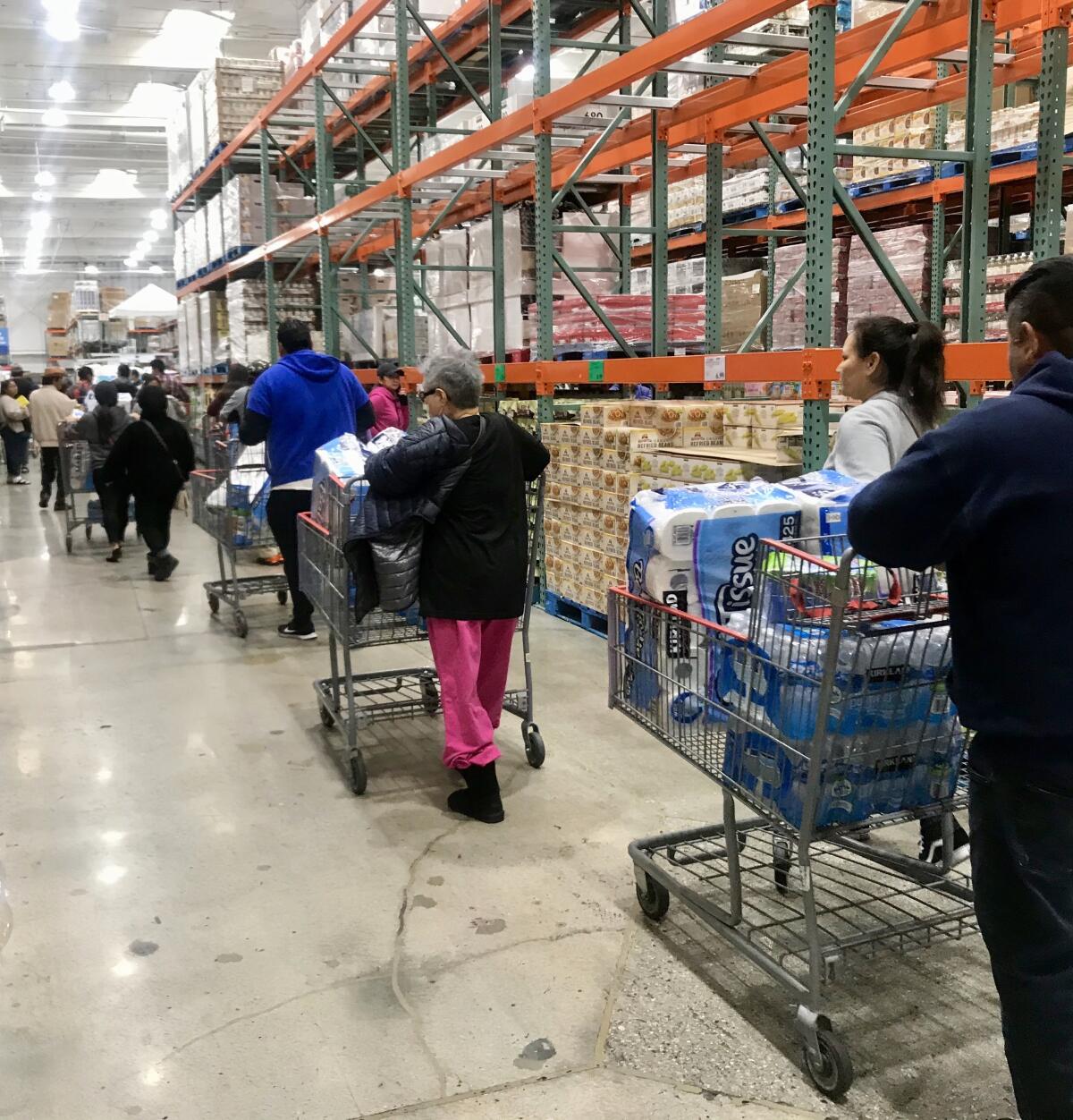 Customers wait in line to buy toilet paper and other supplies at the Costco in Northridge.