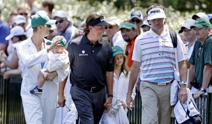 Phil Mickelson walks with Bubba Watson and his wife Angie and their son Caleb during the par three competition before the Masters golf tournament.