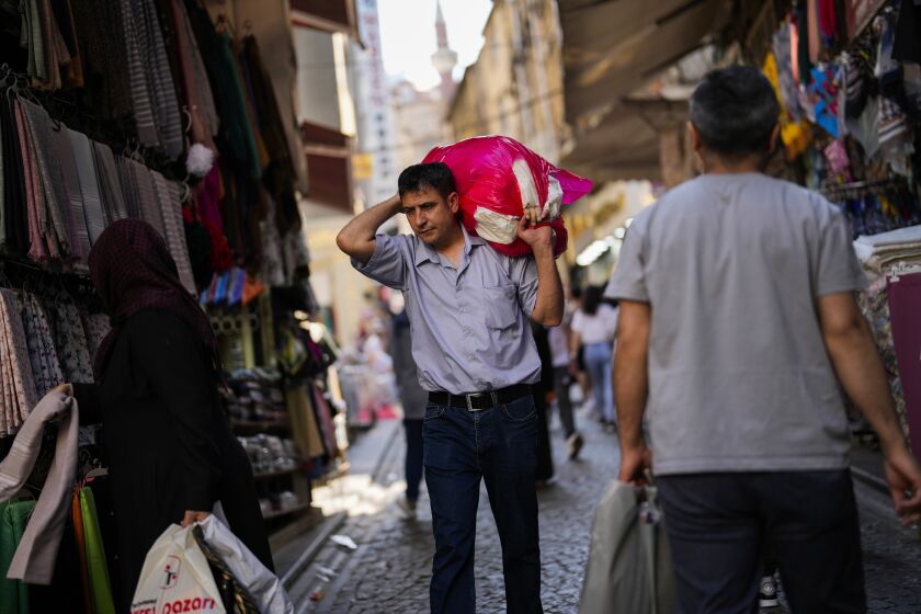 A man carries goods in a street market at Eminonu commercial area in Istanbul, Turkey, Wednesday, June 7, 2023. Turkish President Recep Tayyip Erdogan won reelection last month despite a battered economy and a cost-of-living crisis that experts say are exacerbated by his unconventional economic policies. (AP Photo/Francisco Seco)
