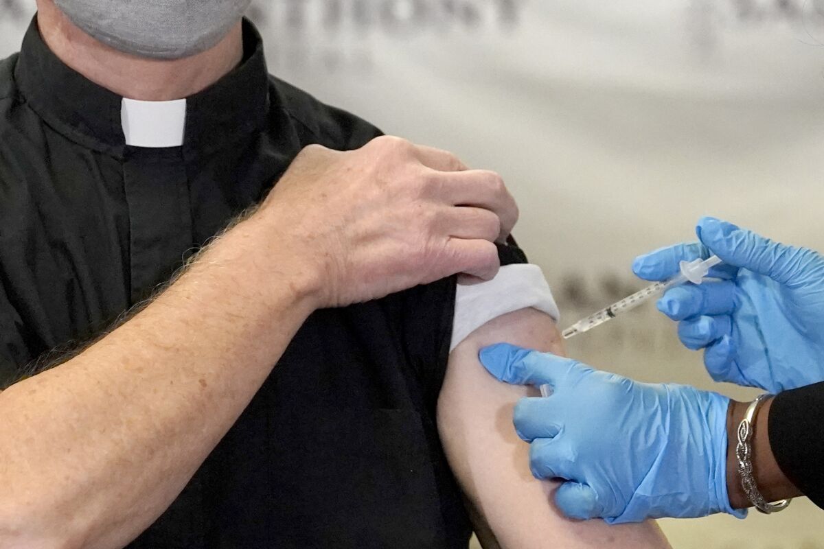 FILE - In this Wednesday, Dec. 23, 2020 file photo, a Catholic pastor receives the first of the two Pfizer-BioNTech COVID-19 vaccinations at a hospital in Chicago. In a growing consensus, religious leaders at the forefront of the anti-abortion movement in the United States are telling their followers that the leading vaccines available to combat COVID-19 are acceptable to take, given their remote and indirect connection to lines of cells derived from aborted fetuses. (AP Photo/Charles Rex Arbogast)