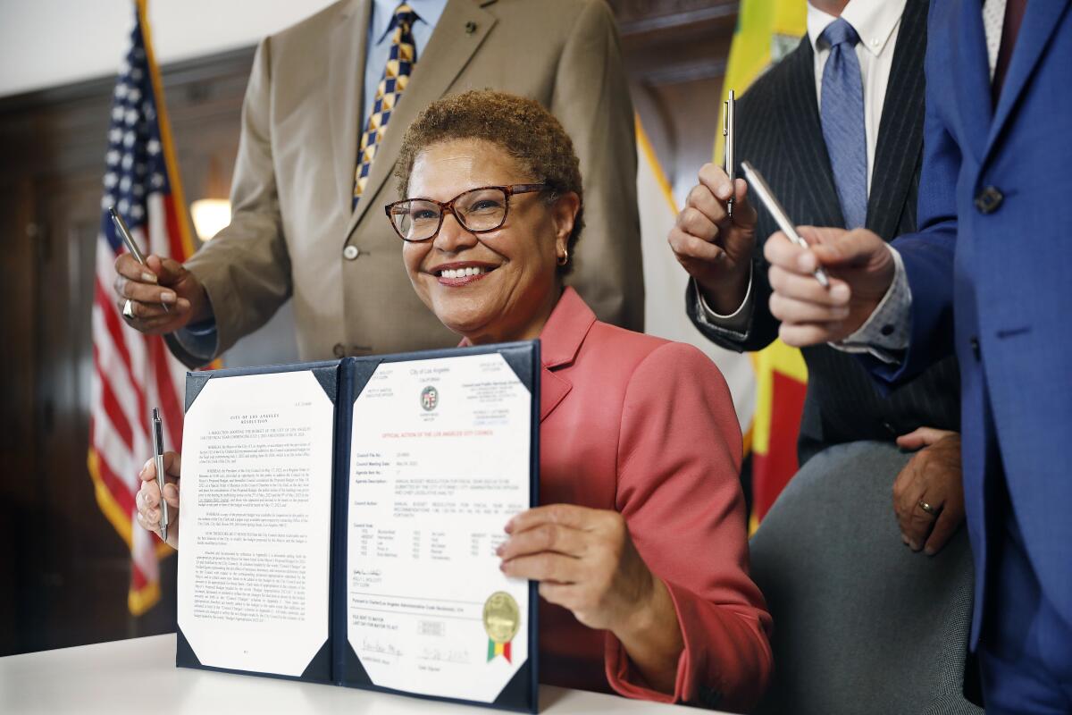 Mayor Karen Bass smiling and holding papers
