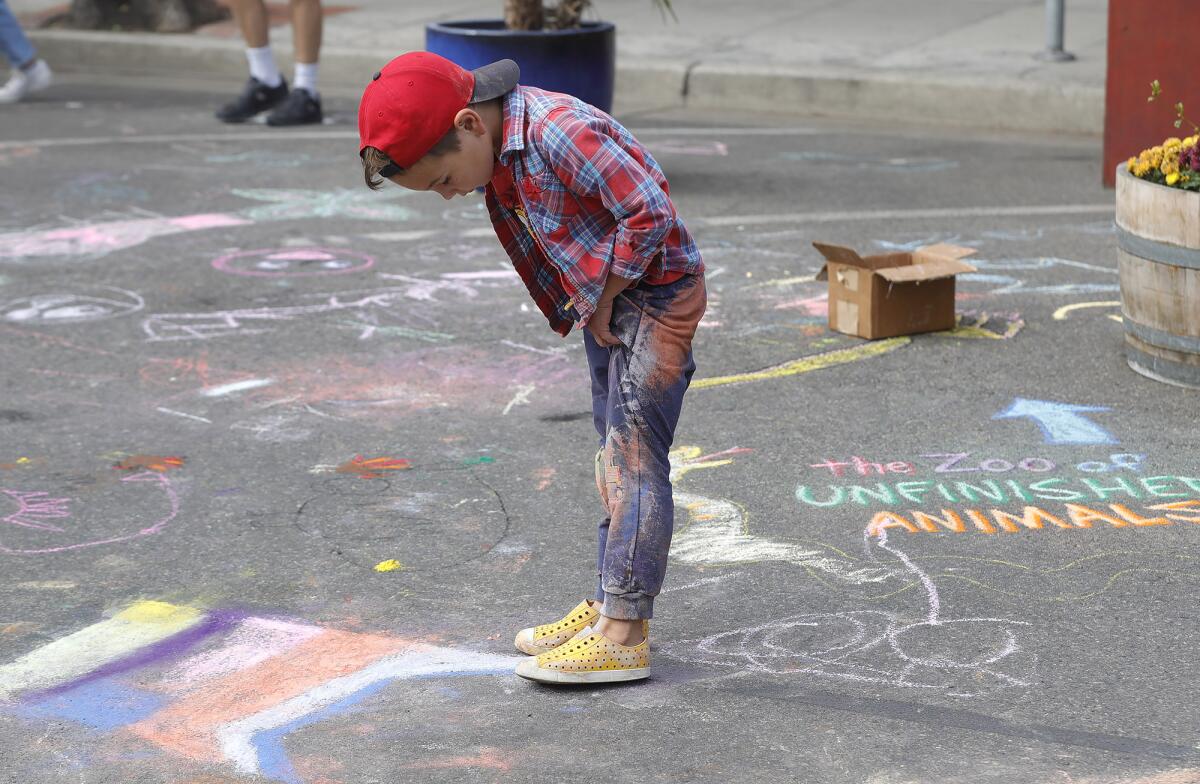 Tanner Upchurch is covered in chalk dust after drawing in the street on the Promenade on Forest in Laguna Beach.