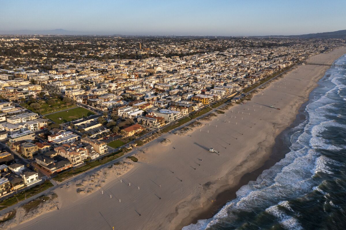 An aerial photo of a sandy beach bordered densely by homes.