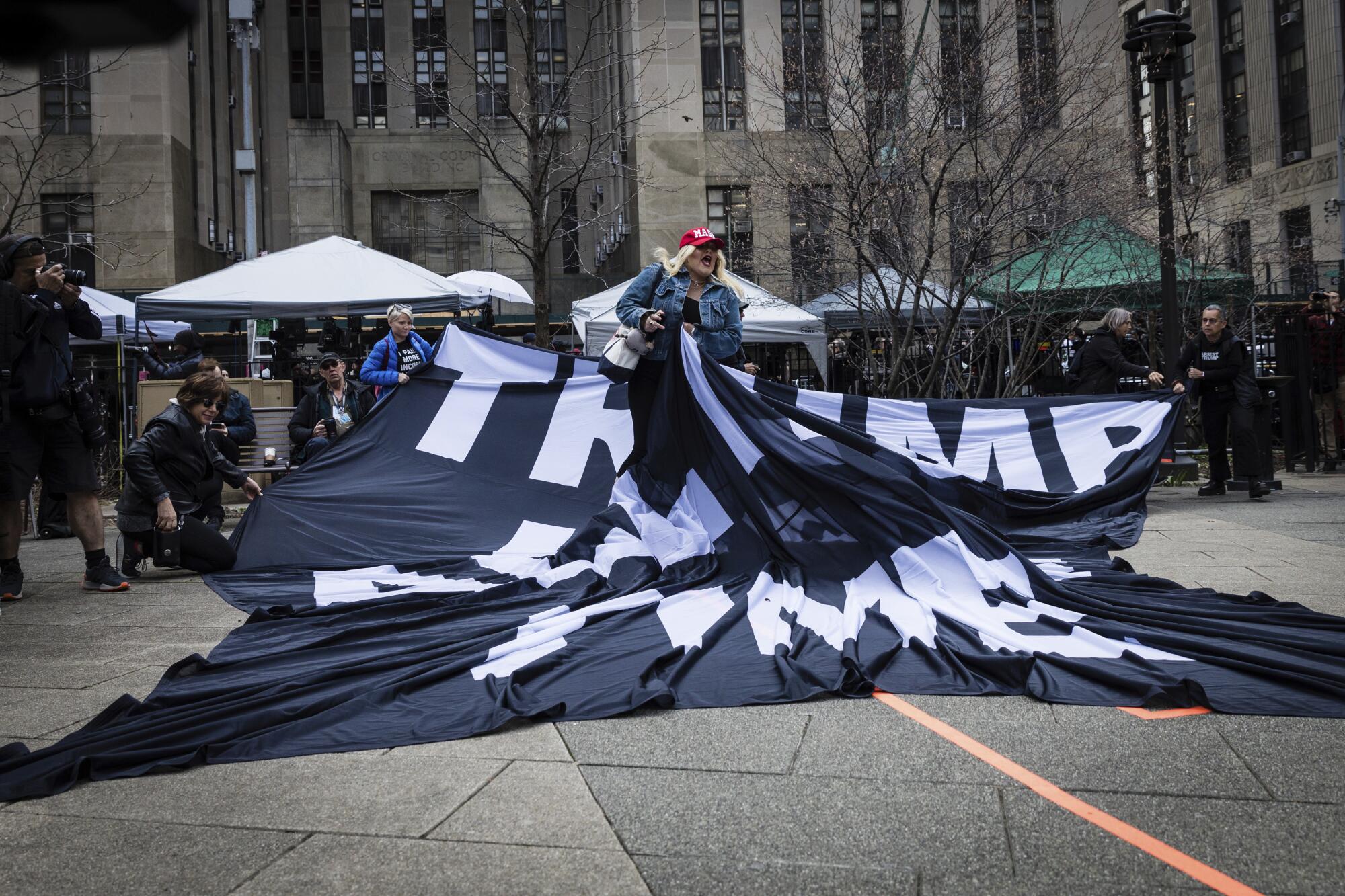 A supporter of former President Trump pulls up an anti-Trump banner off the ground in New York.