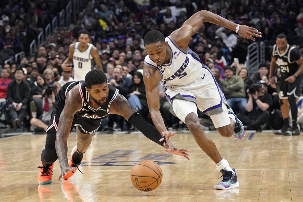 Clippers forward Paul George and Kings guard De'Aaron Fox go after a loose ball 