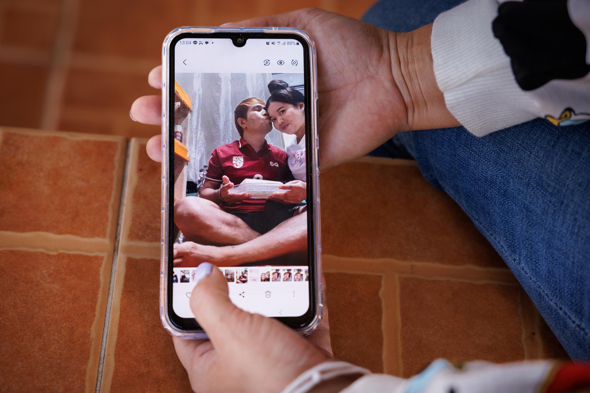 Two hands hold a phone open to a photo of a man and woman.