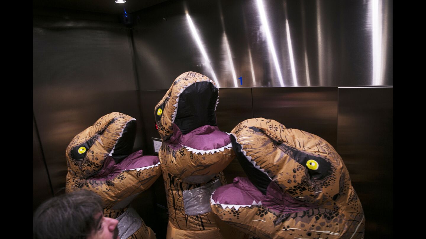 Jurrasic Park T. rex ride an elavator to the second floor of the San Diego Convention Center at Comic-Con 2016. The cosplayers in the dinasaur suits are Kayla Saunders, Kylie Saunders and Kendall Dodd.