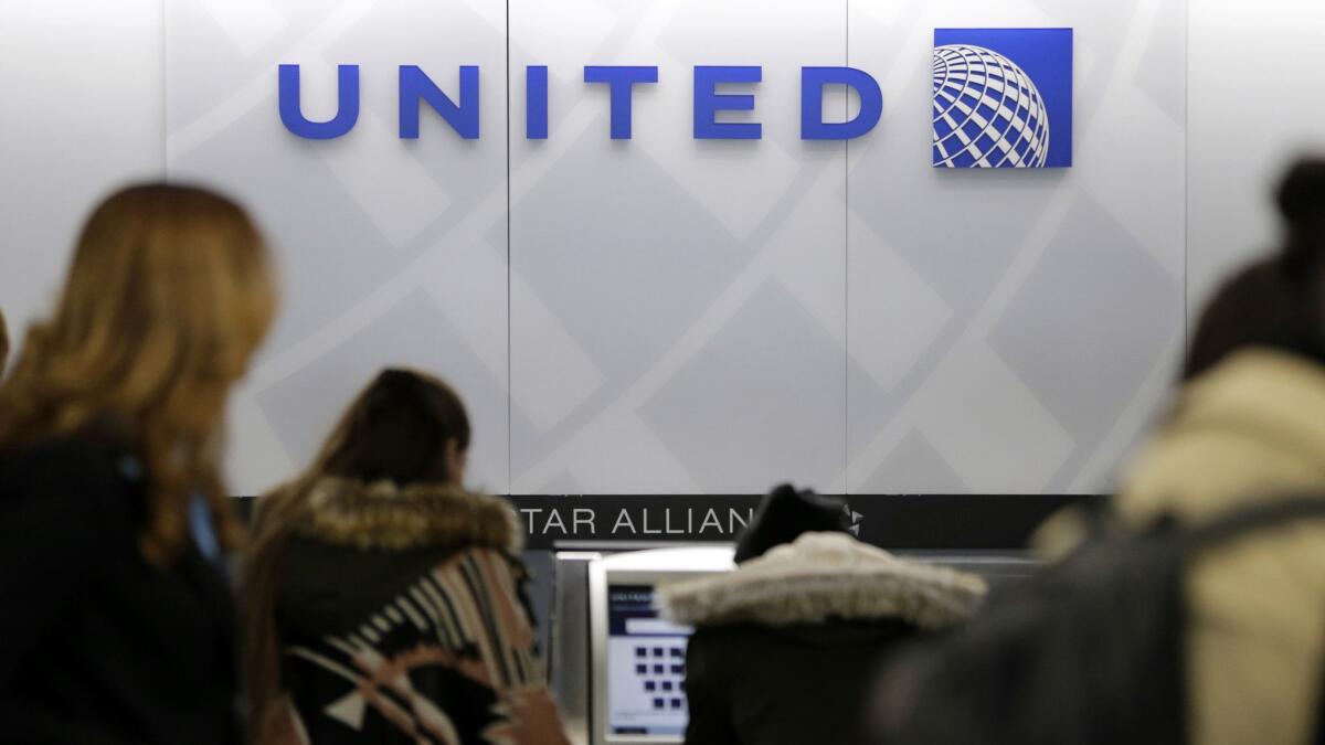 People stand in line at a United Airlines counter at LaGuardia Airport in New York. The airline announced a higher spending minimum to qualify for Premier 1K status on its MileagePlus loyalty reward program.