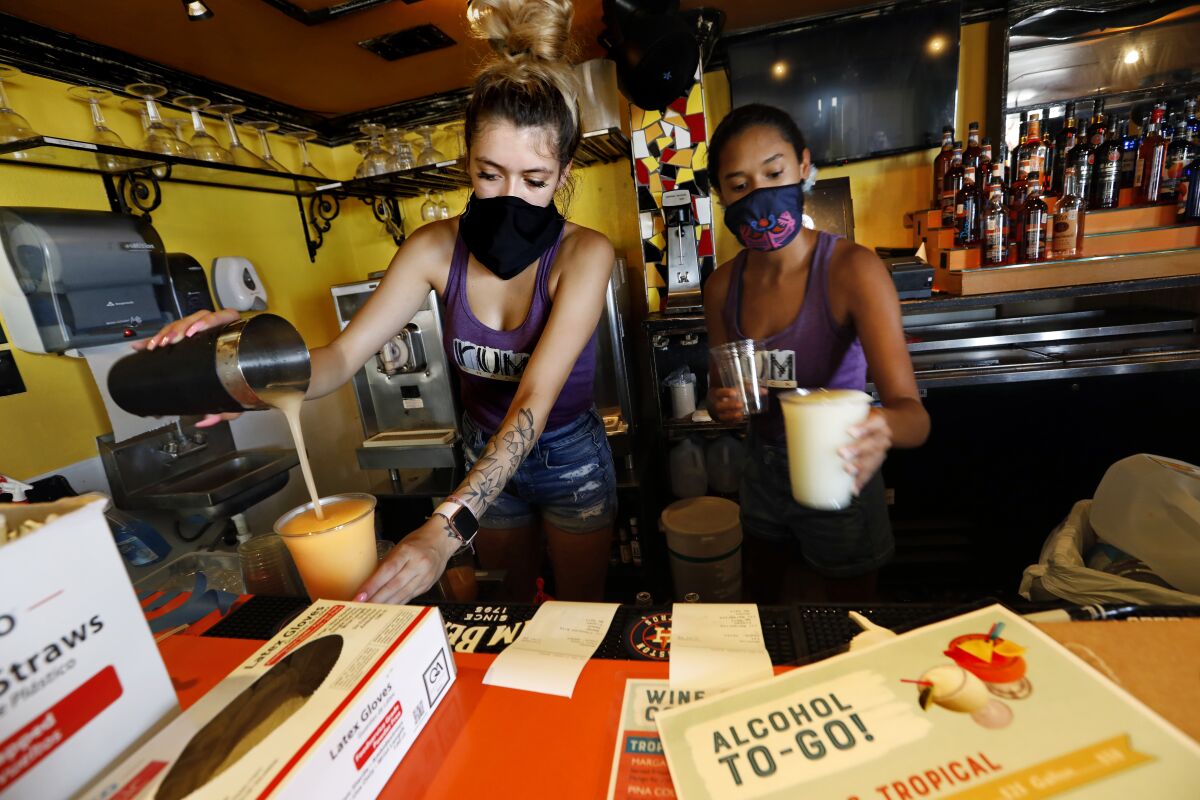 Nila White, left, and Brooklin Lafong make cocktails to go at The Spot, a restaurant and bar in Galveston, Texas.